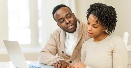 A man and woman reviewing something on a laptop