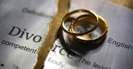 A pair of wedding rings on a ripped piece of paper that says "Divorce"