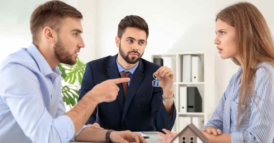 A man and woman sitting across from each other arguing while another man sits between them holding a set of keys