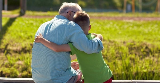 A man hugging his son while looking out at a field