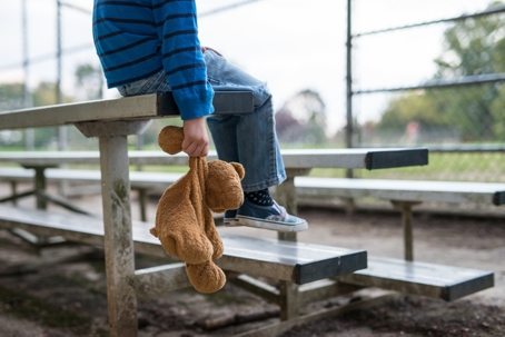 young boy sitting by himself on on bleachers